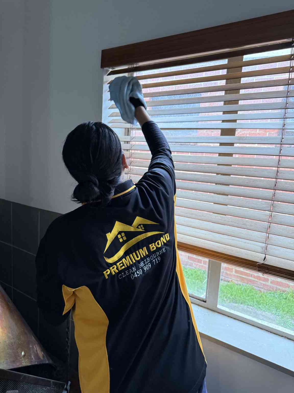 professional cleaner wiping blinds with a cloth