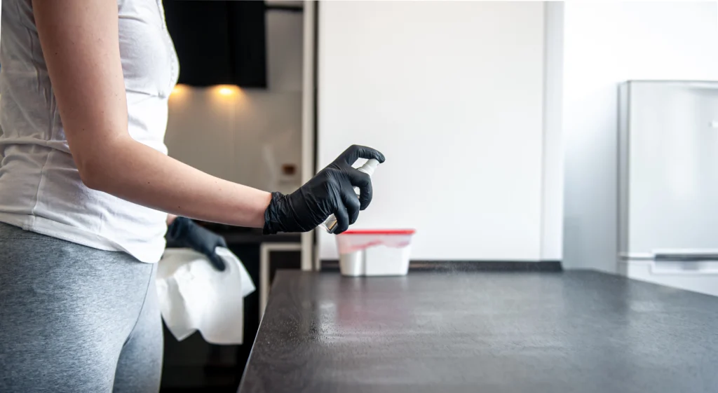 Professional cleaner spraying disinfectant on kitchen countertop