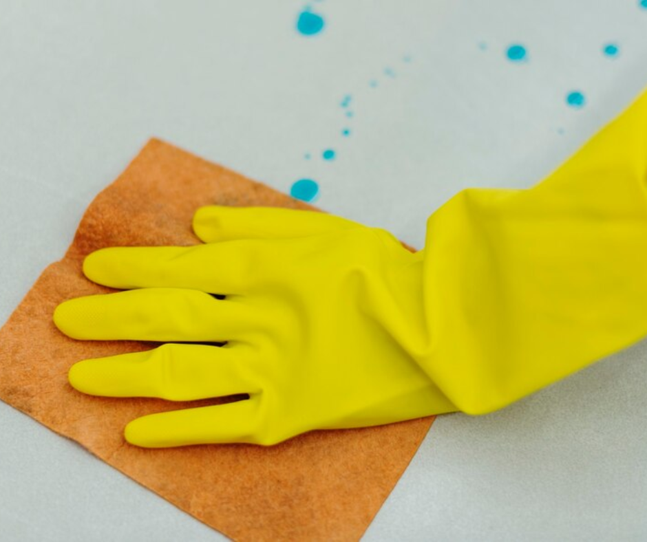 Cleaning surface with yellow rubber gloves and cloth